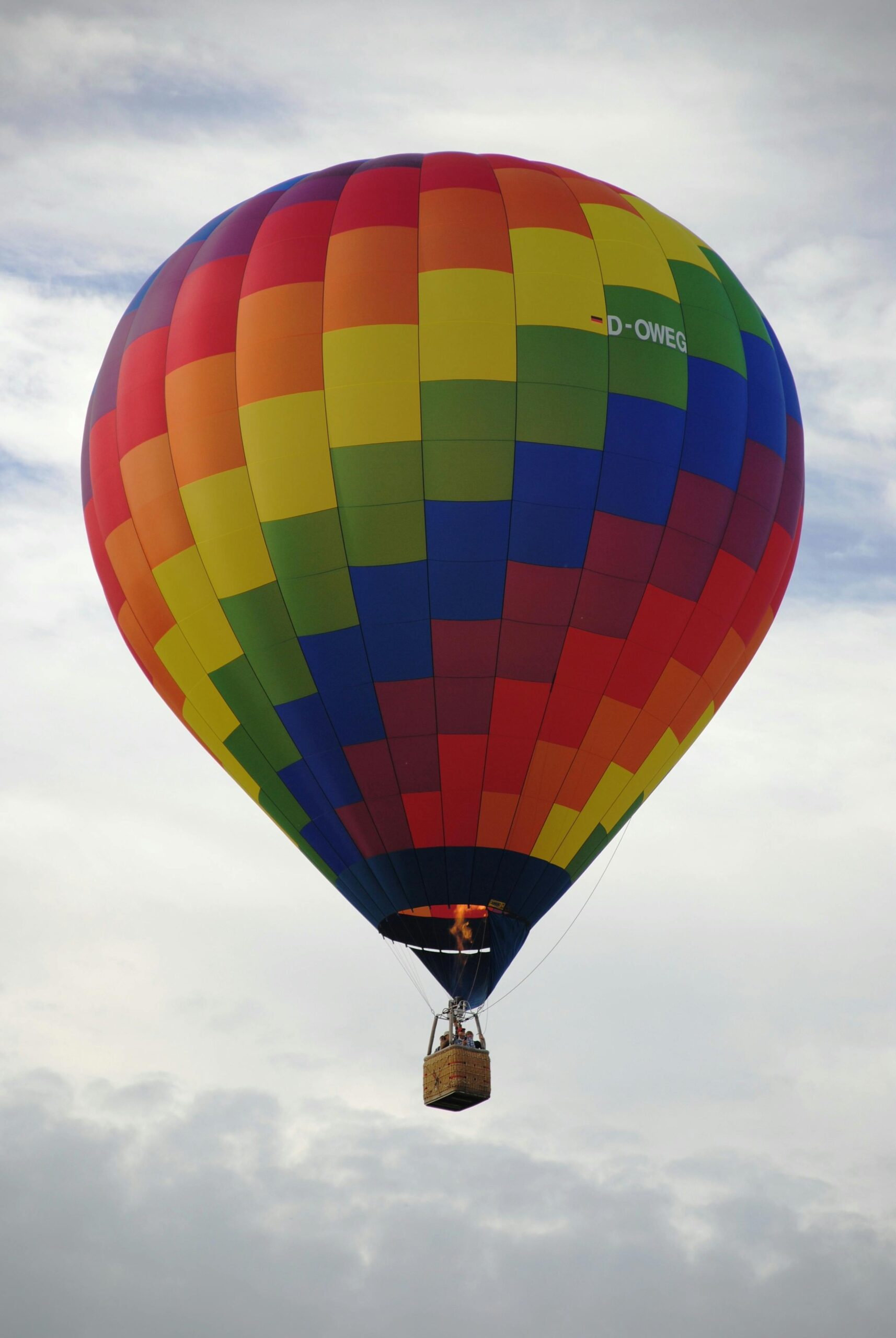 Vibrant rainbow hot air balloon against a cloudy sky, symbolizing adventure and freedom.